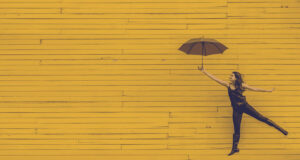 be happy_ Frau mit Schirm springt vor gelber Wand_Pixabay-Berufswege für Frauen