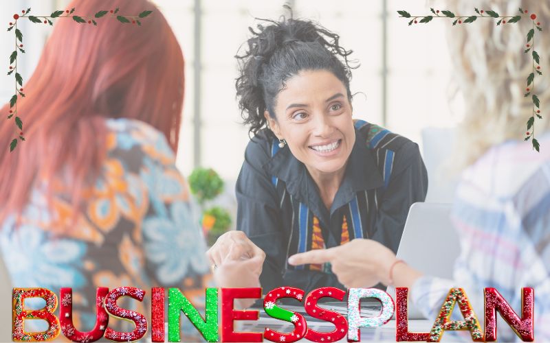 Kurs Dein Businessplan unterm Weihnachtsbaum, Weihnachts-Special 2024. Weiterbildung BerufsWege für Frauen e. V., Frauen sitzen am Tisch, lachen, arbeiten gemeinsam, Schriftzug aus Weihnachtsplätzchen