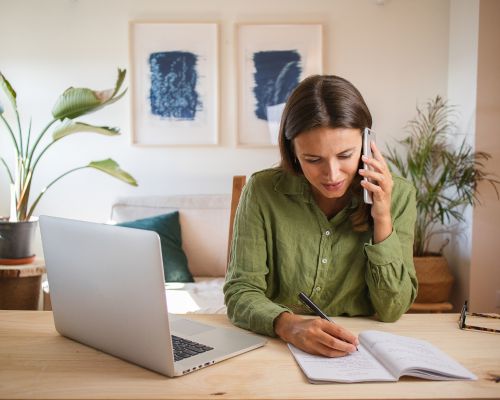 BerufsWege für Frauen und Social Business Women e.V., Weiterbildung für Frauen, WS Buchhaltung ist kein Hexenwerk, Frau arbeitet am PC in ihrem hellen Arbeitsraum zu Hause und telefoniert